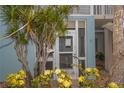 Close-up view of Unit 1's entry with a vibrant flowering bush and a lush tropical tree at 241 Skiff Pt # 1, Clearwater Beach, FL 33767