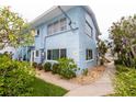 Corner view of a light blue building showing the side entrance with stairway surrounded by lush landscaping at 241 Skiff Pt # 1, Clearwater Beach, FL 33767