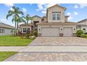Beautiful two-story home with a three-car garage, stone accents, a paver driveway, and well-manicured landscaping at 2724 Coco Palm Cir, Wesley Chapel, FL 33543