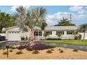 Well-maintained home featuring stone accents, lush landscaping, a circular driveway, and a two-car garage at 6913 Grande Vista S Way, St Petersburg, FL 33707