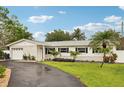 Charming single-story home boasts a well-manicured lawn and beautifully landscaped front yard with palm trees at 6913 Grande Vista S Way, St Petersburg, FL 33707