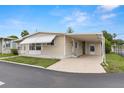 Well-kept single-story home with covered parking, a white door, and established landscaping at 7118 El Meyers St, Zephyrhills, FL 33541