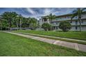 A well-maintained exterior building is enhanced by verdant grass, swaying palms, and convenient covered parking at 960 Virginia St # 202, Dunedin, FL 34698