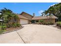 Charming home features a two-car garage, mature landscaping, and a colorful front door at 115 Lake Shore E Dr, Palm Harbor, FL 34684