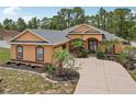 Inviting single-story home with a well-manicured front yard, mature palms and decorative landscaping at 14494 Copeland Way, Brooksville, FL 34604