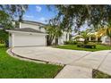 Inviting two-story home featuring a manicured lawn, a two-car garage, and lush tropical landscaping at 16003 Ridley Pl, Tampa, FL 33647