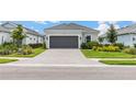 Charming single-story home featuring manicured landscaping, a gray two-car garage door, and a paver driveway at 16126 San Donato Pl, Bradenton, FL 34211