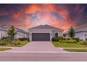 Charming single-story home featuring manicured landscaping, a gray two-car garage door, and a paver driveway at 16126 San Donato Pl, Bradenton, FL 34211