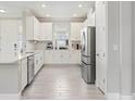 Bright kitchen with white cabinets, stainless steel appliances, gray tiled flooring, and ample counter space at 16126 San Donato Pl, Bradenton, FL 34211