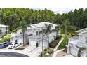 Exterior view of townhomes featuring two-car garages, balconies, and lush tropical landscaping at 1827 Hammocks Ave # 1303, Lutz, FL 33549