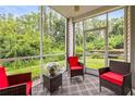 Cozy screened porch with woven furniture, red cushions, and relaxing views of the wooded backyard at 1827 Hammocks Ave # 1303, Lutz, FL 33549