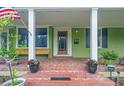 Inviting front porch with brick flooring, decorative plants, and a cozy bench, perfect for relaxing outdoors at 204 W Calhoun St, Plant City, FL 33563