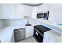 Modern kitchen with stainless steel appliances, white cabinets, and light countertops at 2625 State Road 590 # 1012, Clearwater, FL 33759