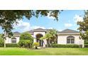Beautiful home showcasing a manicured lawn, mature trees, and an elegant, arched entryway at 2708 Coastal Range Way, Lutz, FL 33559