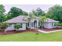 Inviting one-story home with lush lawn, landscaped garden beds, complemented with palm trees for curb appeal at 27511 Hialeah Way, Wesley Chapel, FL 33544
