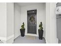 Inviting front entrance featuring a decorative wreath, potted spiral topiary and a neutral colored door mat at 2771 Suncoast Blend Dr, Odessa, FL 33556