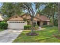 Charming single-Gathering home with a manicured lawn, flower beds, and an attached two-car garage at 2990 Longbrooke Way, Clearwater, FL 33760