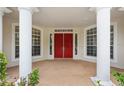 Close-up of the front entrance featuring grand red double doors, white columns, and beautiful windows at 3062 Sutton Woods Dr, Plant City, FL 33566