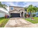 Charming two-story home with a well-maintained lawn and landscaping featuring palm trees and flowering plants at 533 Vista Ridge Dr, Ruskin, FL 33570