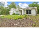 Angle view of a cozy single-story home with an attached garage, landscaped yard, and inviting front porch at 5422 Wilkins Trl, Brooksville, FL 34602