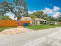 Charming home boasts a well-manicured lawn, mature trees, and a warm, inviting exterior during the day at 6425 S Adelia Ave, Tampa, FL 33616