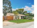 Charming home boasts a well-manicured lawn, mature trees, and a warm, inviting exterior during the day at 6425 S Adelia Ave, Tampa, FL 33616