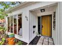 Close up of the front entrance showcasing the bright yellow front door, modern house numbers, and accent rocks at 675 64Th S Ave, St Petersburg, FL 33705