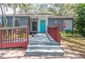 Charming home featuring a red railing, an accessible ramp, and a bright blue front door at 715 W 109Th Ave, Tampa, FL 33612