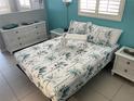 Bright bedroom with a tropical themed bedspread and white wicker furniture at 800 Bayway Blvd # 14, Clearwater Beach, FL 33767