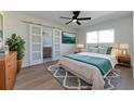 Bright bedroom featuring a king bed, ceiling fan, wood floors, and sliding doors leading to the bathroom at 8444 15Th N Way, St Petersburg, FL 33702