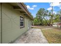 Shows the exterior of the house with light green siding and a concrete walkway on the side at 9213 W Robson St, Tampa, FL 33615