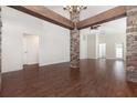Spacious living room featuring hardwood floors and stylish stone columns with wood beam accents at 10847 Kirkwall Port Dr, Wimauma, FL 33598