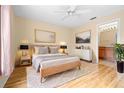 Bright bedroom featuring a queen-sized bed, a ceiling fan, and an ensuite bathroom with cherry wood cabinets at 11546 52Nd E Ct, Parrish, FL 34219