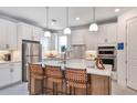 Modern kitchen with white cabinets, stainless steel appliances, quartz countertops, and breakfast bar at 1576 Valier Pt, Zephyrhills, FL 33541