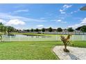 Tranquil backyard with lush lawn and views of the serene pond behind a white picket fence at 449 Bahama Grande Blvd, Apollo Beach, FL 33572