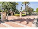 Community entrance featuring brick pavers, pillars, decorative lighting, and lush landscaping at 5029 Camberley Ln, Oldsmar, FL 34677