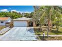 Charming single-story home featuring stone facade, two-car garage, and mature landscaping at 7613 Bramblewood Dr, Port Richey, FL 34668