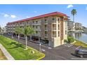 Condo building featuring balconies, covered parking, palm trees, and manicured lawn at 105 Island Way # 126, Clearwater Beach, FL 33767