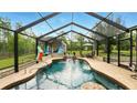 Inviting screened-in pool with waterfall feature and poolside seating area at 15348 Glossy Ibis Rd, Weeki Wachee, FL 34614