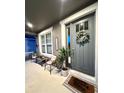 Charming front porch featuring a gray front door, window, wicker seating, and a 'Home Sweet Home' mat at 33560 Castaway Loop, Wesley Chapel, FL 33543