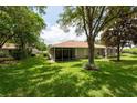 Spacious backyard with lush green lawn, mature trees, and screened lanais at 4228 Silver Star Dr, Spring Hill, FL 34609