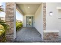 Inviting entryway features stone accents, a decorative glass door, neutral siding, and a brick-paver landing at 4679 Emprise Way, Land O Lakes, FL 34638