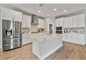 Modern kitchen with stainless steel appliances, sleek white cabinetry, quartz countertops, and a center island at 4679 Emprise Way, Land O Lakes, FL 34638