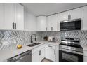 Modern kitchen featuring white cabinets, stainless steel appliances, and stylish backsplash at 6738 Criswell N Ave, St Petersburg, FL 33709