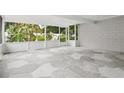 Enclosed patio featuring tile flooring, white brick wall, and views of lush greenery at 7503 Winchester Dr, Tampa, FL 33615