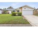 Inviting home exterior with stone details, manicured lawn, and a two-car garage at 11762 Barb Ct, Seminole, FL 33778