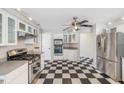 This kitchen boasts stainless steel appliances, white cabinets and black and white checkered flooring at 15420 Aubrey Ave, Spring Hill, FL 34610
