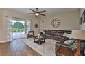 Cozy living room featuring a large leather sectional, wood-look tile, and sliding glass doors to a screened pool at 3212 E Merrin Rd, Plant City, FL 33567