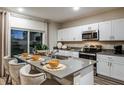 Bright kitchen with white cabinets, stainless steel appliances, island with seating, and sliding glass doors at 37206 Sagemoor Dr, Zephyrhills, FL 33541