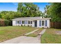 Charming single-story home featuring a well-manicured lawn, blue shutters, and inviting curb appeal at 3906 W Rogers Ave, Tampa, FL 33611